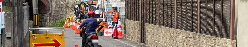 高槻市の管路点検業務現場で交通誘導警備中の警備員1(2024.04.05)